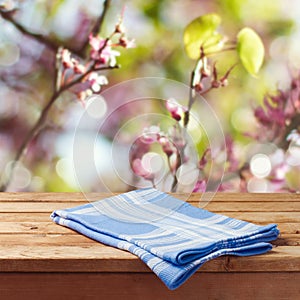 Empty wooden table with tablecloth over spring garden bokeh background for product montage