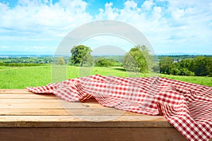 Empty wooden table with tablecloth over summer background