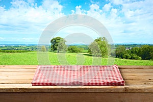 Empty wooden table with tablecloth over summer background