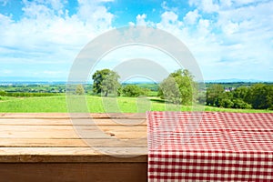 Empty wooden table with tablecloth over summer background