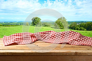 Empty wooden table with tablecloth over summer background