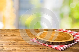 Empty wooden table with tablecloth and wooden board over abstract background