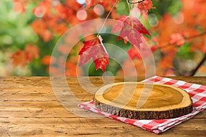 Empty wooden table with tablecloth and wooden board over autumn nature park background