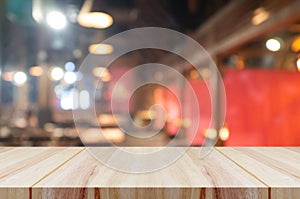 Empty wooden table top with blurred coffee shop or restaurant interior background