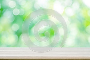 Empty wooden table top with blurred green natural abstract background.