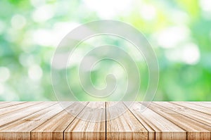 Empty wooden table top with blurred green natural background.
