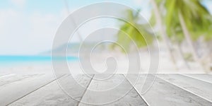 Empty wooden table top with out of focus lights bokeh tropical ocean beach background with palm trees and island