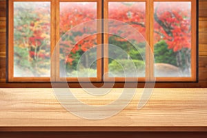 Empty Wooden table top with wood window and autumn garden display for product concept