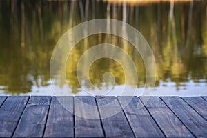 Empty wooden table and view of blurred calm lake background near spring forest. For product display