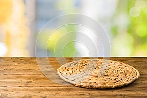 Empty wooden table with wicker round placemat over abstract bokeh background