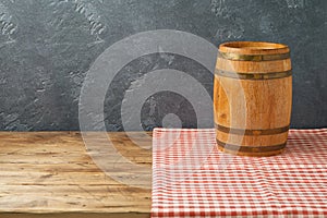 Empty wooden table with wine barrel and tablecloth over black wall background