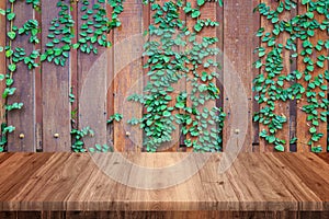 Empty wooden table with wood and vine wall background