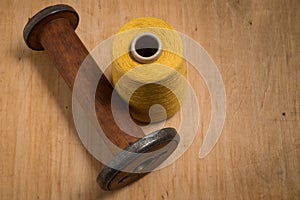 Empty Wooden Thread Spool Beside Yellow Thread