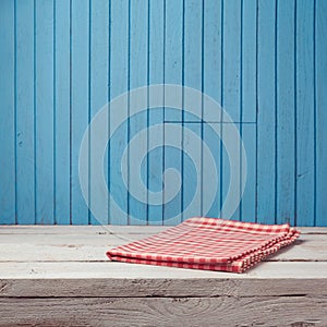 Empty wooden white table with checked tablecloth over blue wall