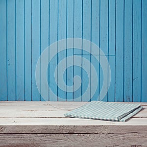 Empty wooden white table with tablecloth over blue wooden wall.