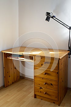 empty wooden writing desk, in a corner with white walls and sun