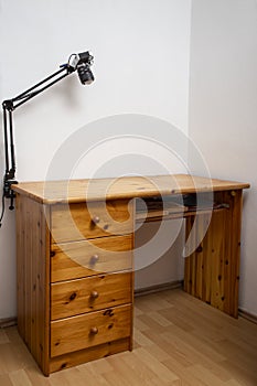 empty wooden writing desk, in a corner with white walls, and wooden flooring