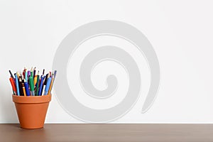 Empty work desk in home office with white wall and pencils and stationery on wooden table. Work, study, school