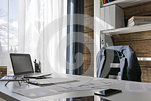 Empty workplace with office desk and chair, jacket on the chair, photo