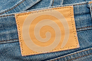 Empty worn leather patch on blue jeans. Empty space for writing. Blank leather jeans label