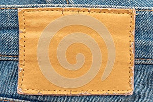 Empty worn leather patch on blue jeans. Empty space for writing. Blank leather jeans label