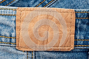 Empty worn leather patch on blue jeans. Empty space for writing. Blank leather jeans label