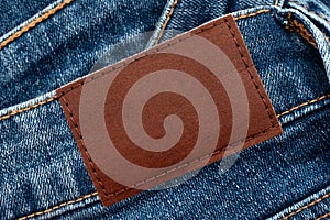 Empty worn leather patch on blue jeans. Empty space for writing. Blank leather jeans label