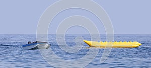 An empty yellow banana boat and a speedboat lying in the sea