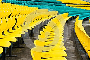 Empty yellow plastic chairs in symmetrical rows in a cricket stadium