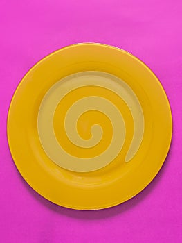 Empty yellow plate on pink