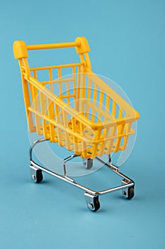 Empty yellow shopping basket on a blue background. Shopping and crisis concept