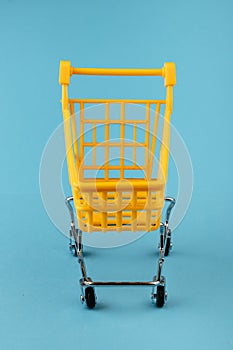 Empty yellow shopping basket on a blue background. Shopping and crisis concept