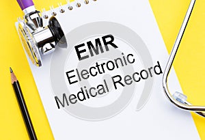 EMR Electronic Medical Record text concept written on notepad with stethoscope