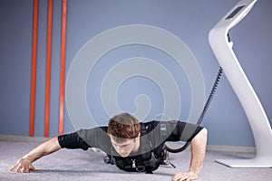 EMS male doing push ups in gym while connected to electric muscle stimulator