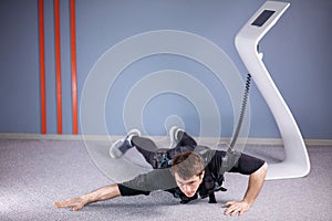 EMS male doing push ups in gym while connected to electric muscle stimulator
