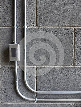 EMT PIPE Electrical Metallic Tubing and junction box on the grey bricks wall in construction site on building