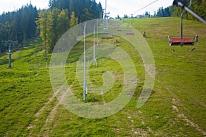 Emtpy chairlift in ski resort. Mountains and hills with in Summer with green trees