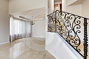 Emtpy house interior. Marble staircase with black wrought iron r