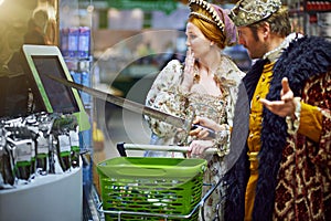 En garde ye dastardly thing. a king and queen trying to use a touchscreen monitor while shopping in a modern grocery