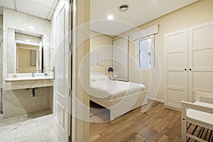 en-suite bedroom with bathroom with marble tiles, white wood