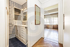 An en-suite toilet in a vintage home with nobel wooden flooring and white cabinets in the bathroom with lots of drawers