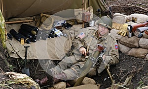 Enactor dressed as American world war two soldier resting in trench.