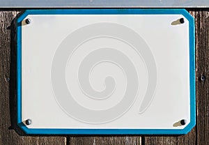 enamel, metal or pottery sign on a rustic wooden wall. blue frame, under a bright turquoise sky.