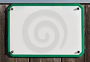 enamel, metal or pottery sign on a rustic wooden wall. green frame, under a bright turquoise sky.