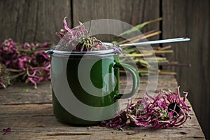 Enameled cup of healthy echinacea tea with tea infuser, dry coneflower herbs.