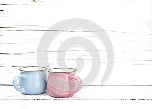 Enameled mugs in retro style on an old wooden background