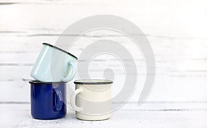 Enameled mugs in retro style on an old wooden background