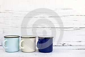 Enameled mugs in retro style on an old wooden background