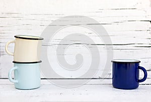 Enameled mugs in retro style on an old wooden background