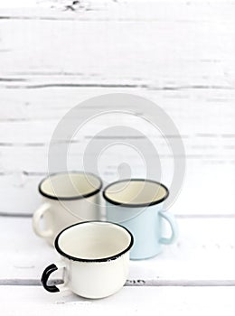Enameled mugs in retro style on an old wooden background